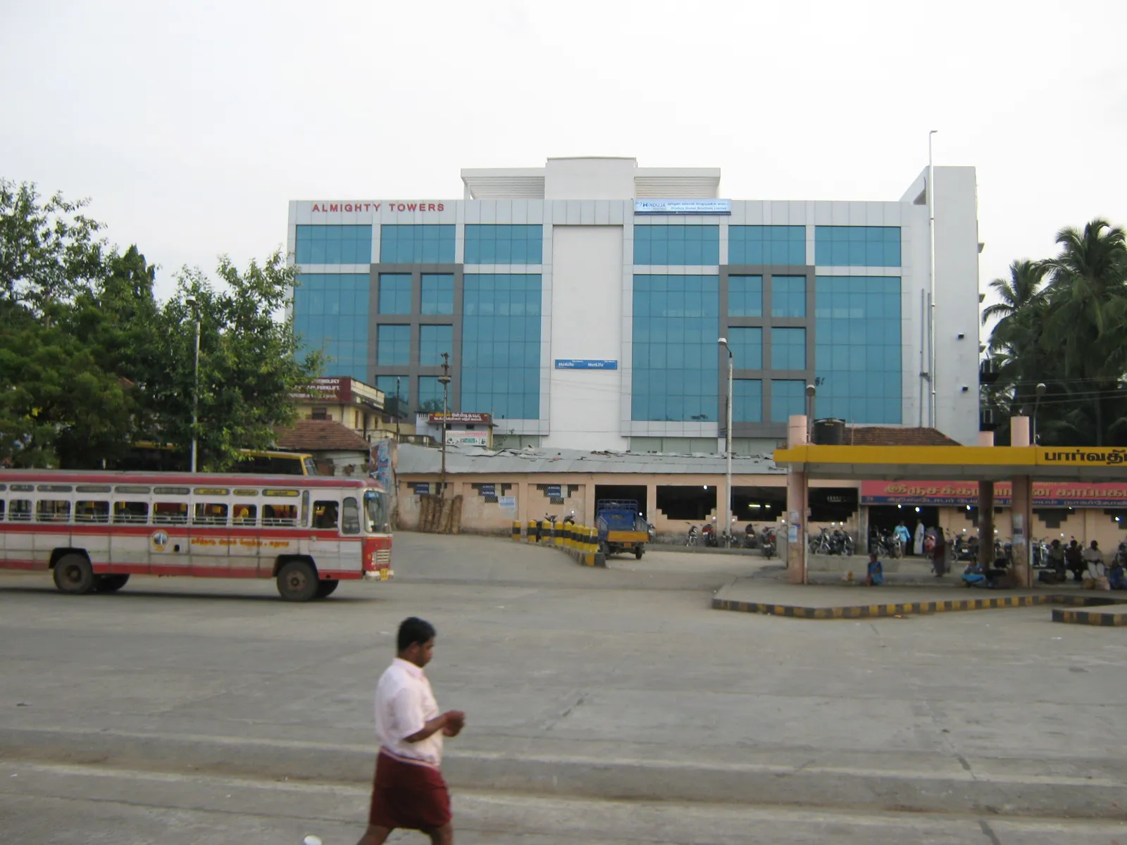 A TNSTC town bus outside the Nagercoil bus stand at Vadasery, with the glass-fronted Almighty Towers behind