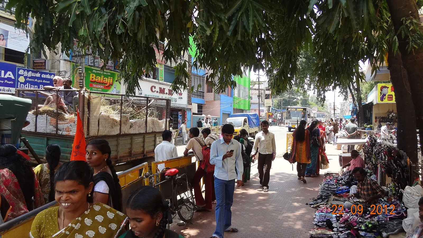 A busy shopping street in downtown Nagercoil with pavement stalls and a town bus
