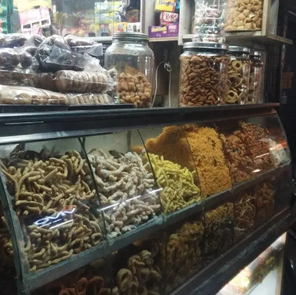 Glass counter of South Indian savouries and jars of snacks inside RajaGopal Sweet Stall, a chips shop in Nagercoil